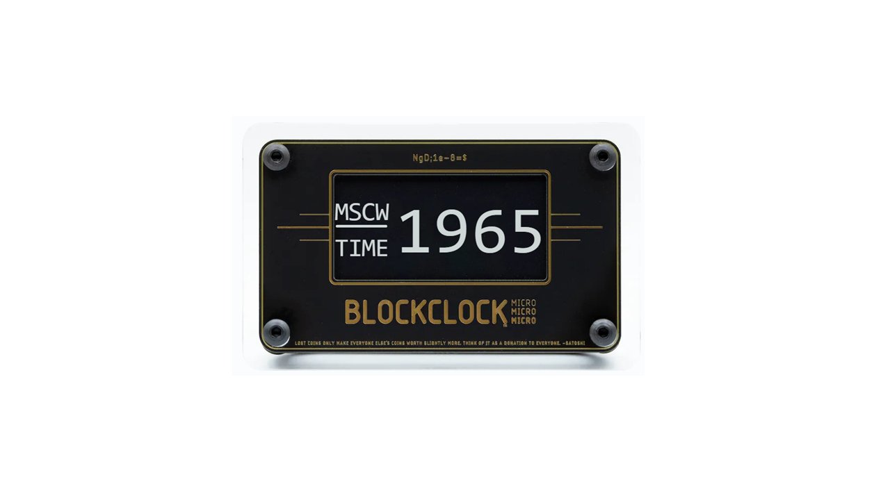 The Blockclock Micro by UTXO Dreams features a black display that shows "MSCW TIME 1965" in white text. It is labeled with "BLOCKCLOCK MICRO" at the bottom and is adorned with decorative gold lines and screws on a white frame, potentially offering real-time tracking of bitcoin network information.